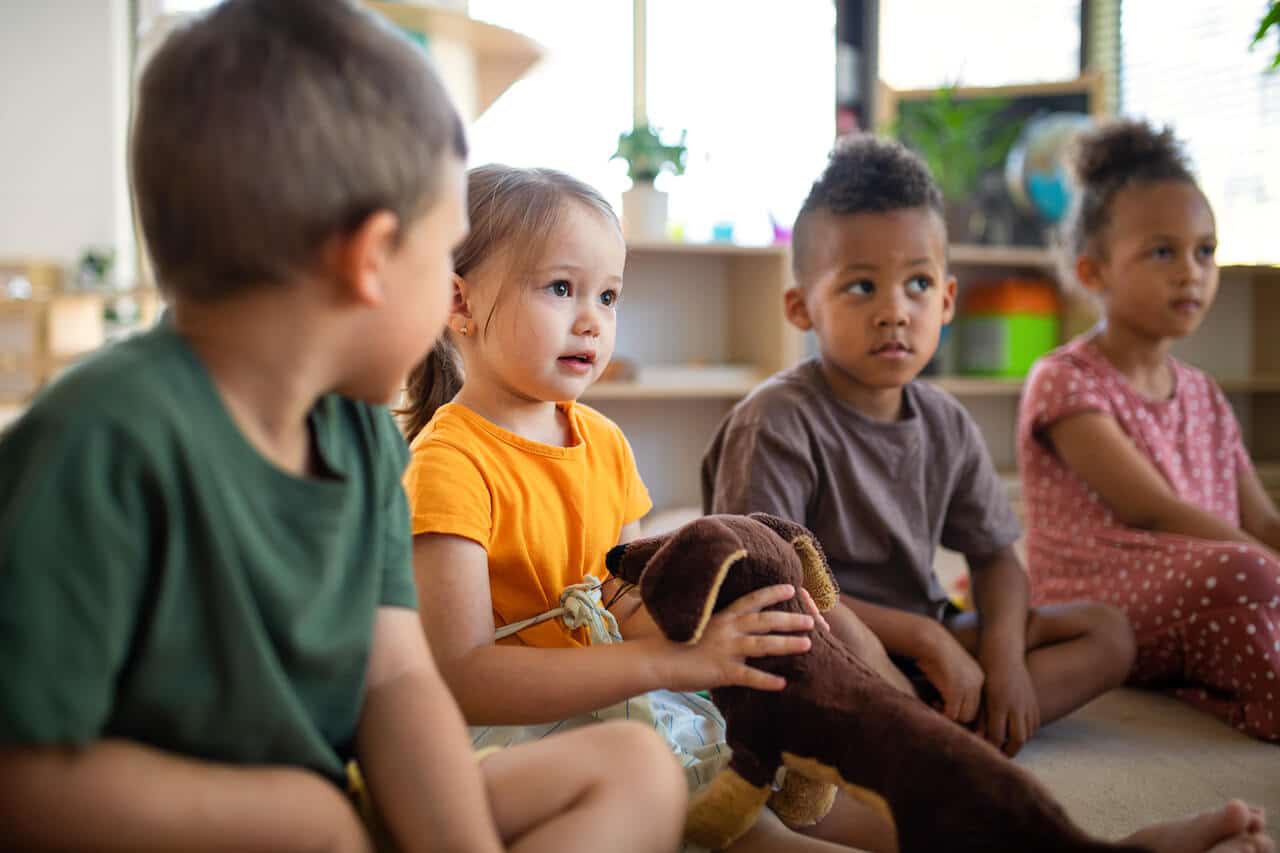 Eingewöhnung in der Kita erfolreich abgeschlossen. Kinder sitzen beisammen und erzählen.