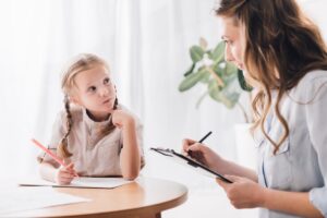 Lernentwicklungsgespräch in der Grundschule - Kind und Lehrkraft sprechen an einem Tisch